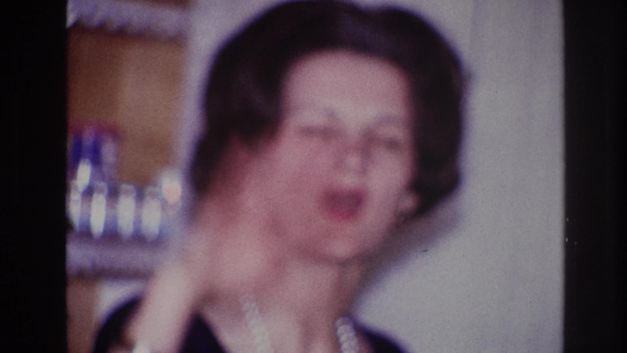 Adult woman in a dark dress raises her hand while speaking indoors.