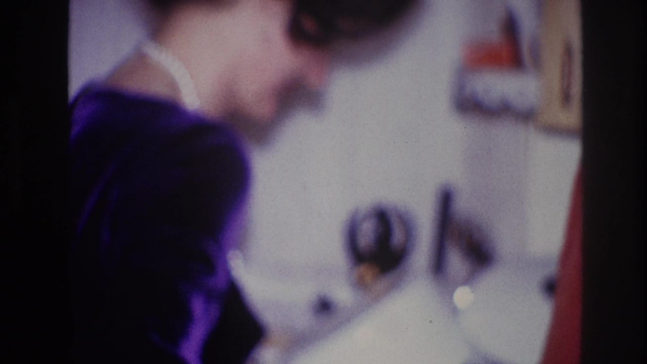 1967 Ottawa 8mm frame showing a woman in a dark top and white collar turning away near an indoor party setting.