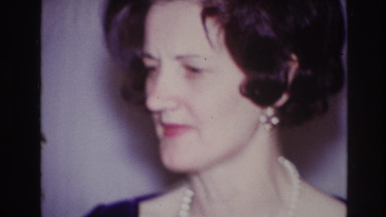 1967 Ottawa home-movie close-up of a woman with short dark hair, pearl necklace, earrings, and dark blue clothing.