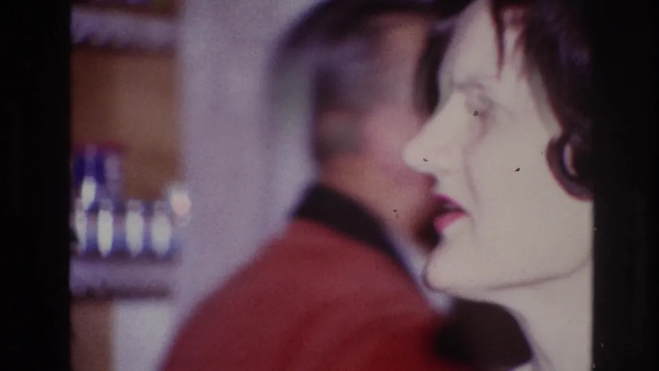 A younger woman in profile appears in the foreground as the older man remains blurred behind her in the 1967 Ottawa interior.