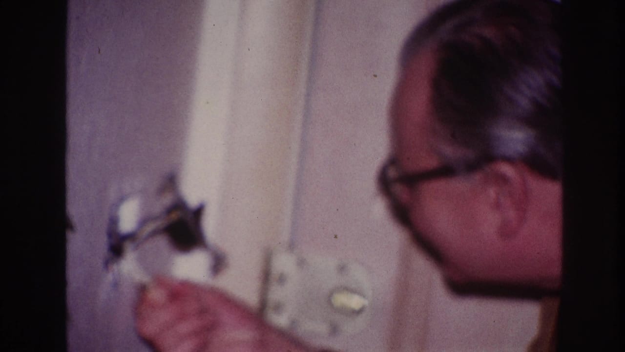 A man in glasses appears to inspect an interior wall fixture in 1967 Ottawa home-movie footage.