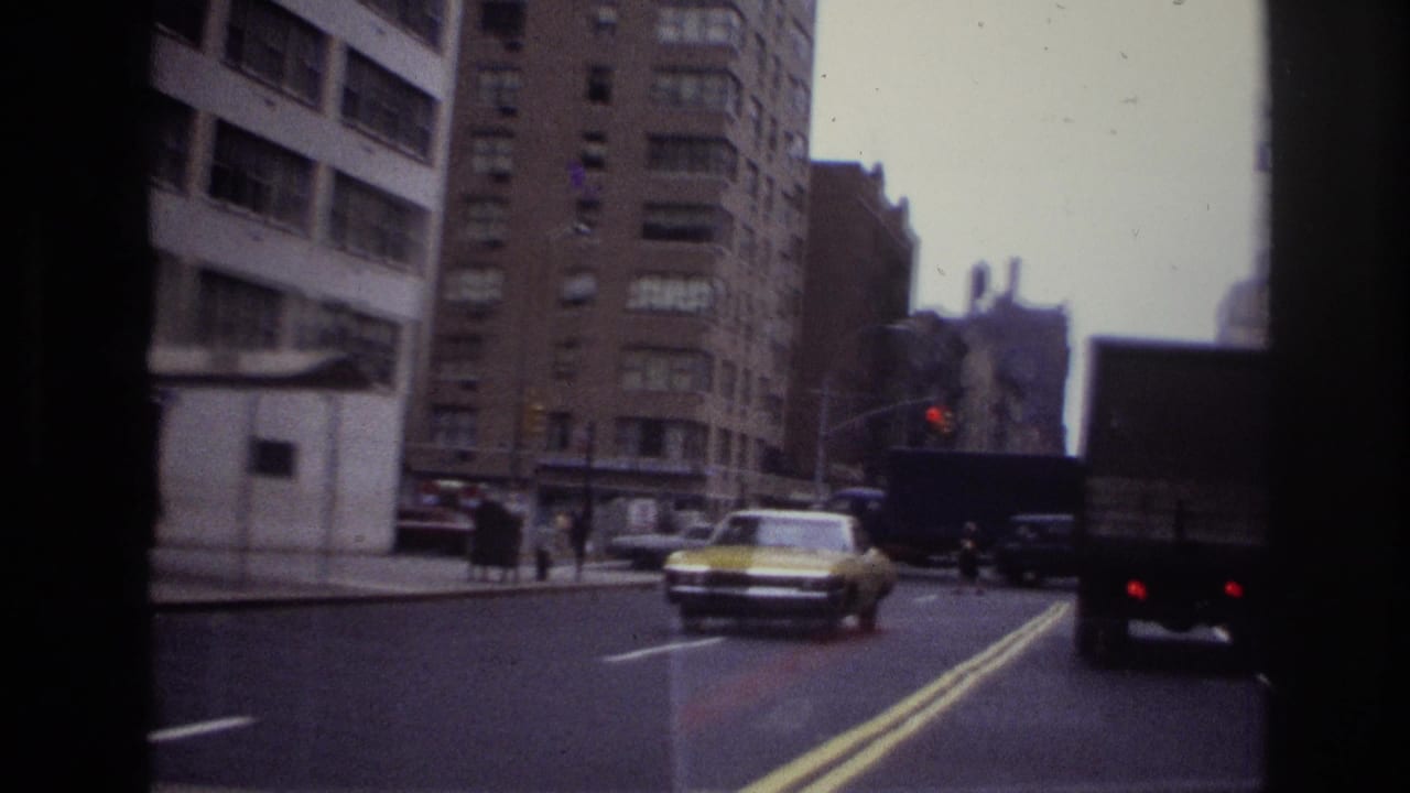 Busy city street with cars, pedestrians, tall buildings, and a yellow taxi.
