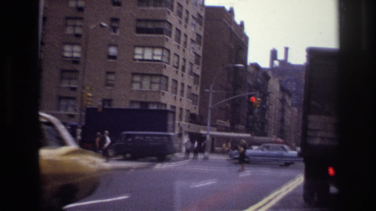 Ottawa city intersection with cars, pedestrians, traffic lights, and brick apartment blocks in a handheld 8mm frame.