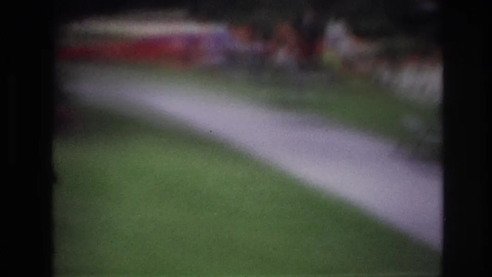 Blurred final frame of the 1967 Ottawa garden clip, with the walkway and lawn dominating and flowerbeds indistinct beyond.