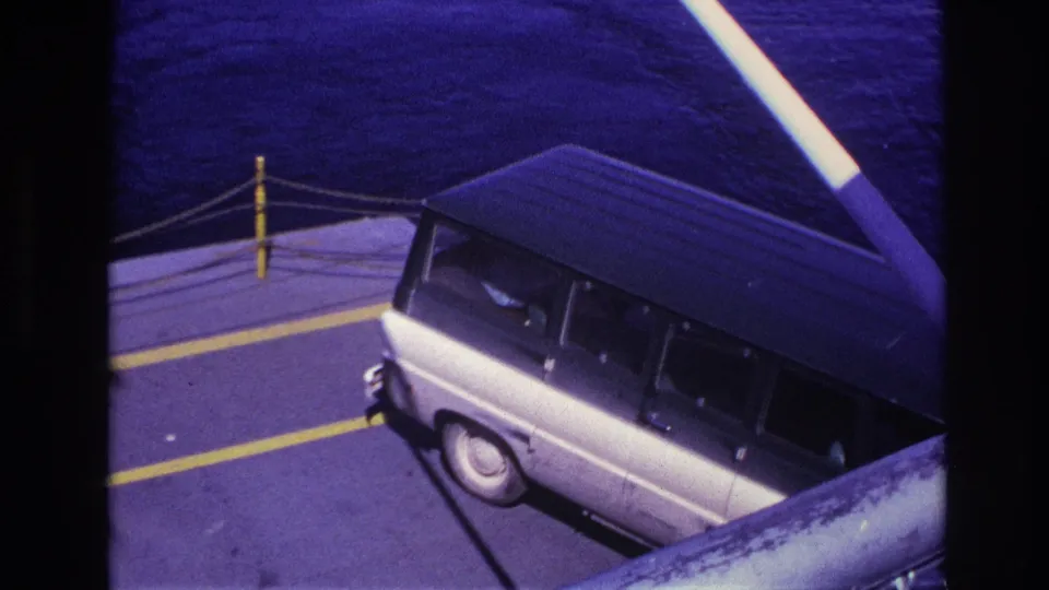 1967 Ottawa-area ferry view from above, with a white van, deck rail ropes, yellow lines, and dark water in the background.