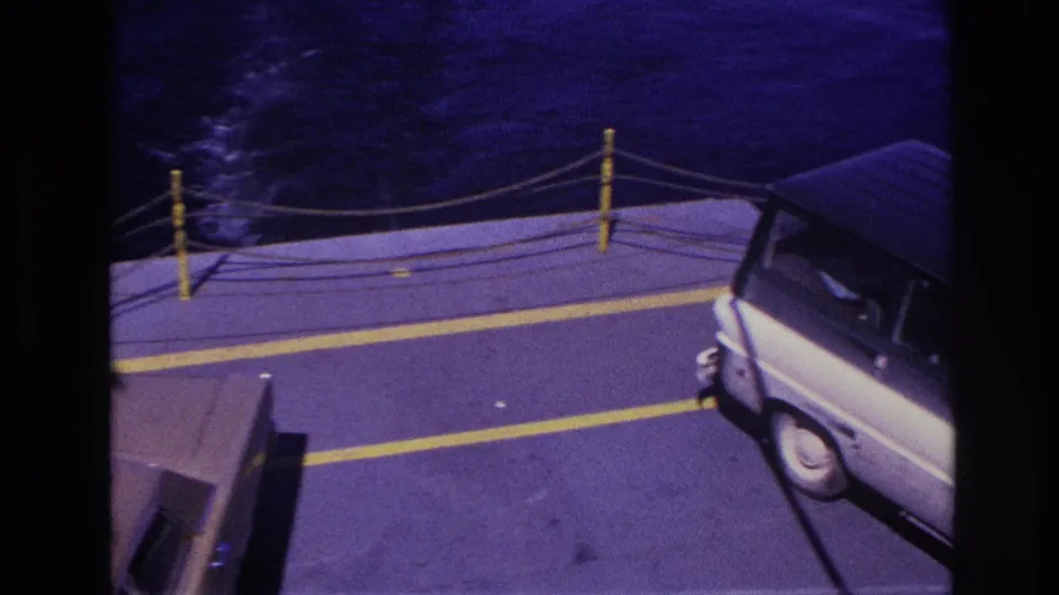 High-angle 1967 Ottawa-area ferry shot with part of a car entering frame and a white van near the deck edge.