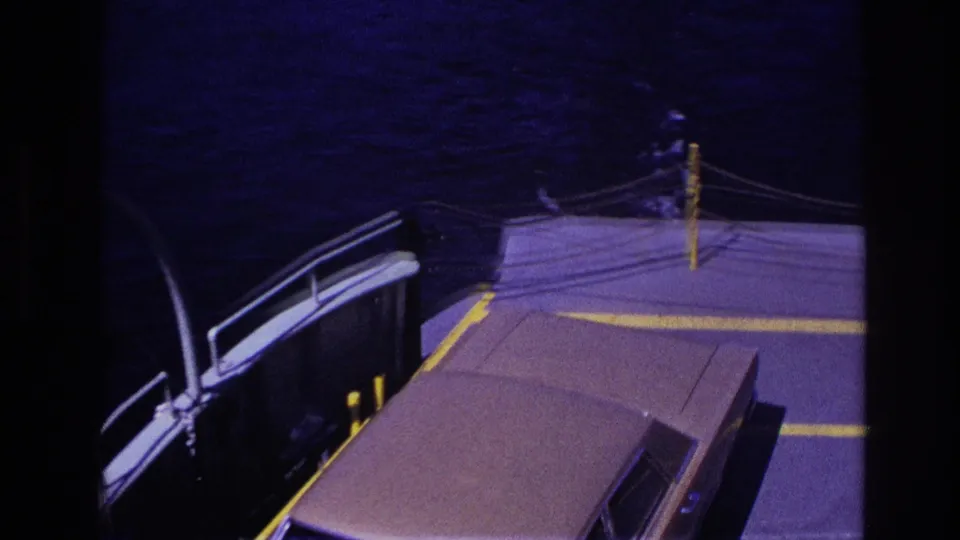 1967 Ottawa home-movie frame showing a ferry deck with yellow markings, railing, water, and a partial vehicle roof.