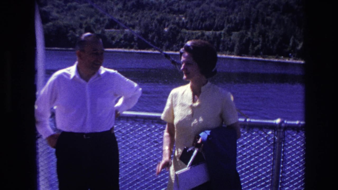 1967 Ottawa home-movie frame of a man in a white shirt and a woman holding a purse near a ferry railing.