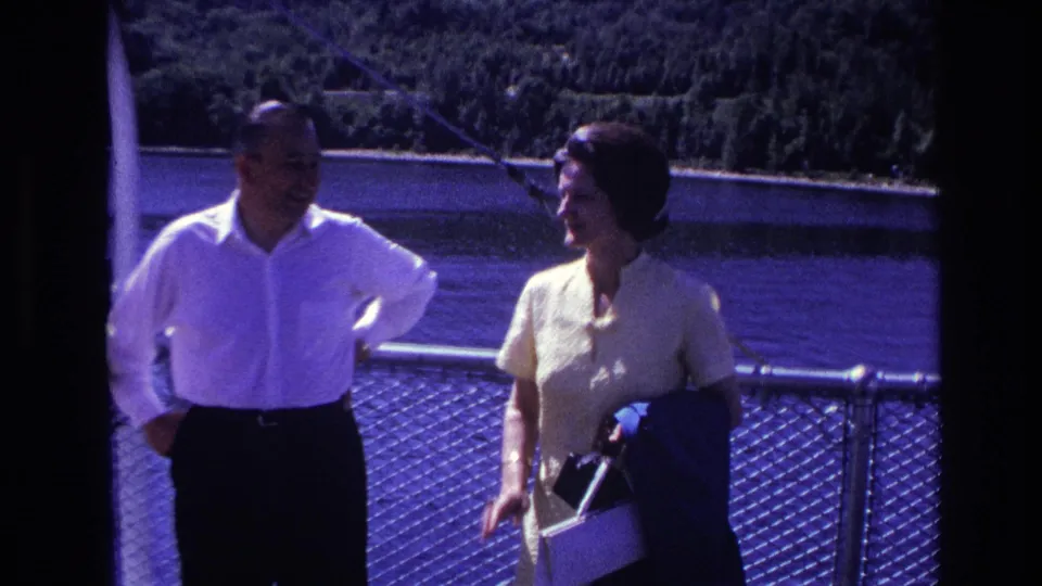 1967 Ottawa home-movie frame of a man in a white shirt and a woman holding a purse near a ferry railing.