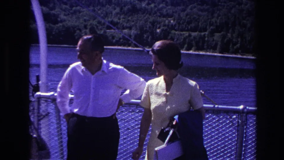 1967 Ottawa home-movie frame of two adults on a ferry deck, with the woman holding a purse and jacket.