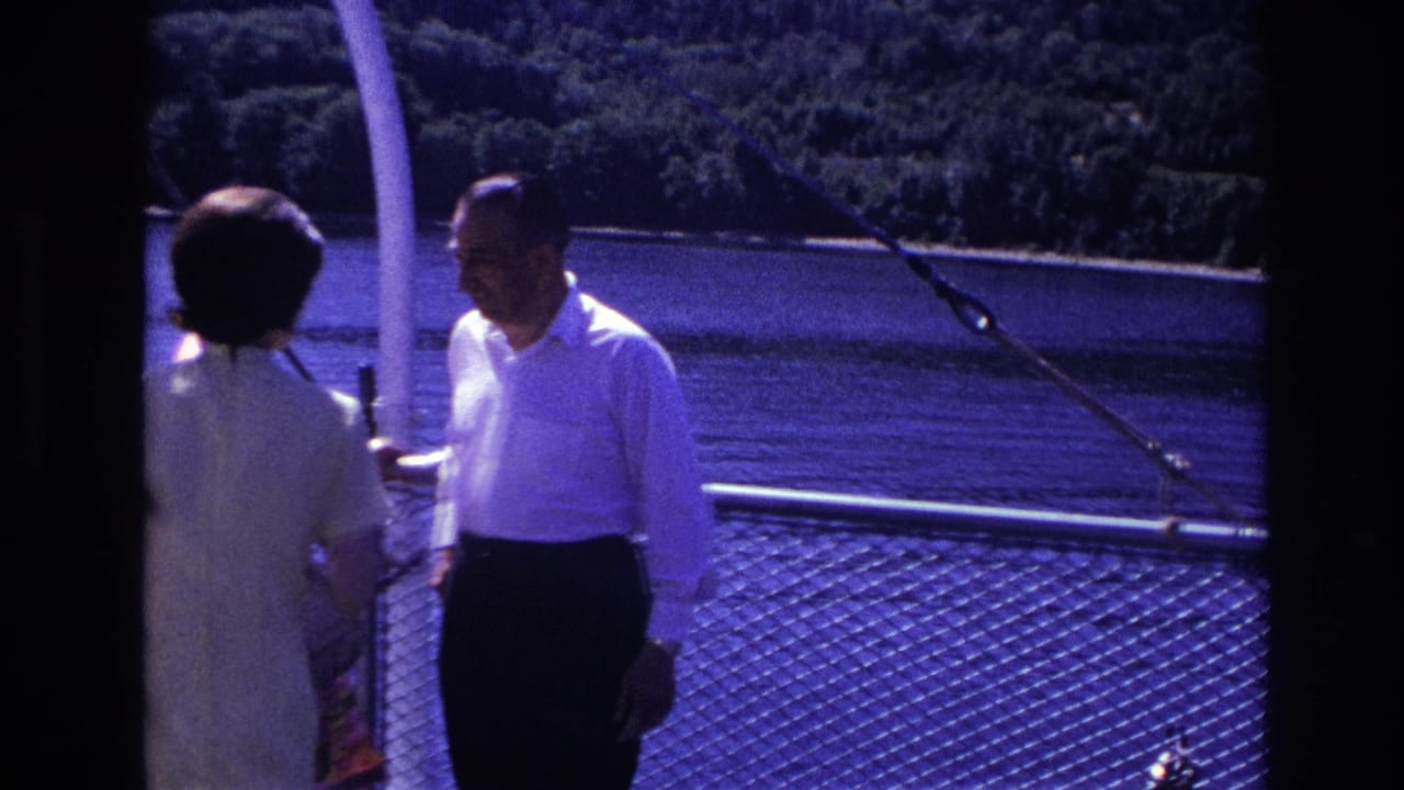 A man in a white shirt and a woman in a light dress stand aboard a boat in the supplied 1967 Ottawa home-movie footage.