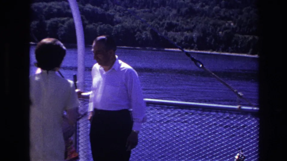 A man in a white shirt and a woman in a light dress stand aboard a boat in the supplied 1967 Ottawa home-movie footage.
