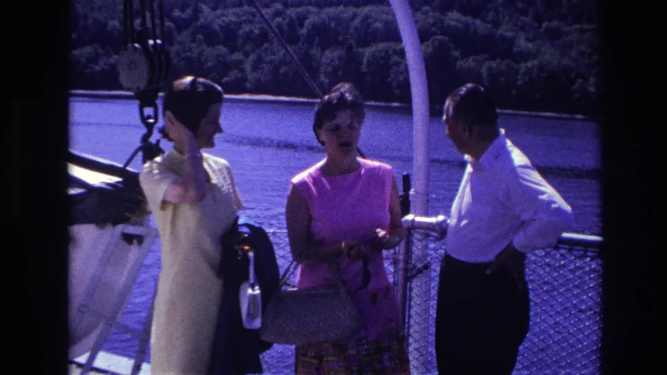 The 1967 Ottawa home-movie frame shows three adults on a boat deck, including a woman in pink and a man in a white shirt.