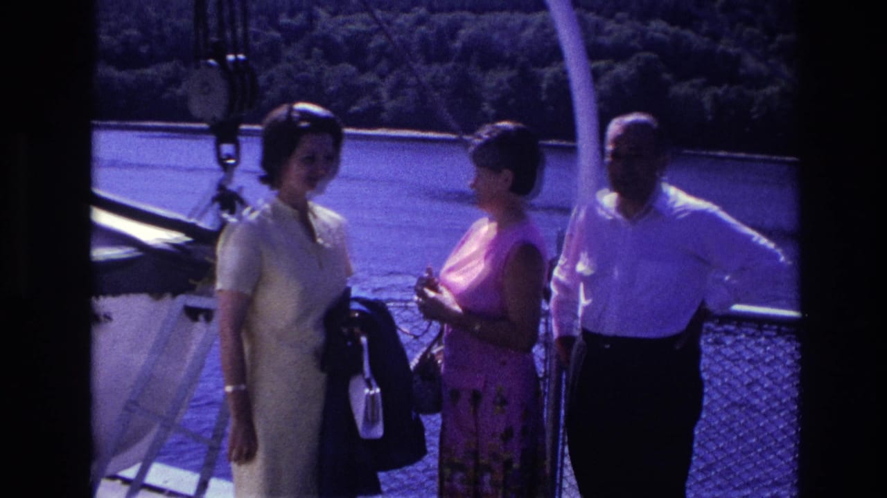 Two women in light summer dresses and a man in a white shirt stand on a boat deck in Ottawa archival footage.