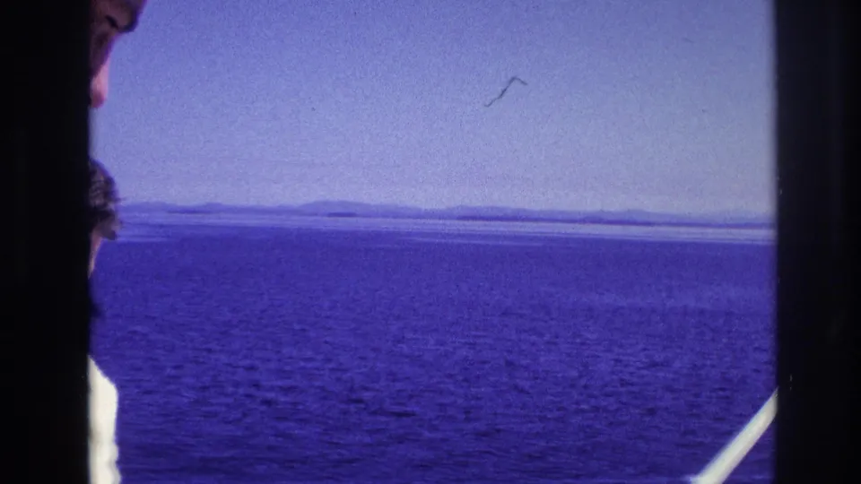 Wide Ottawa-area water view from the boat, with a distant low shoreline under a blue sky in 1967 home-movie footage.