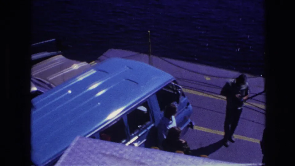 Elevated 1967 Ottawa home-movie view of a blue van and passengers on a ferry deck with water beyond the rail.
