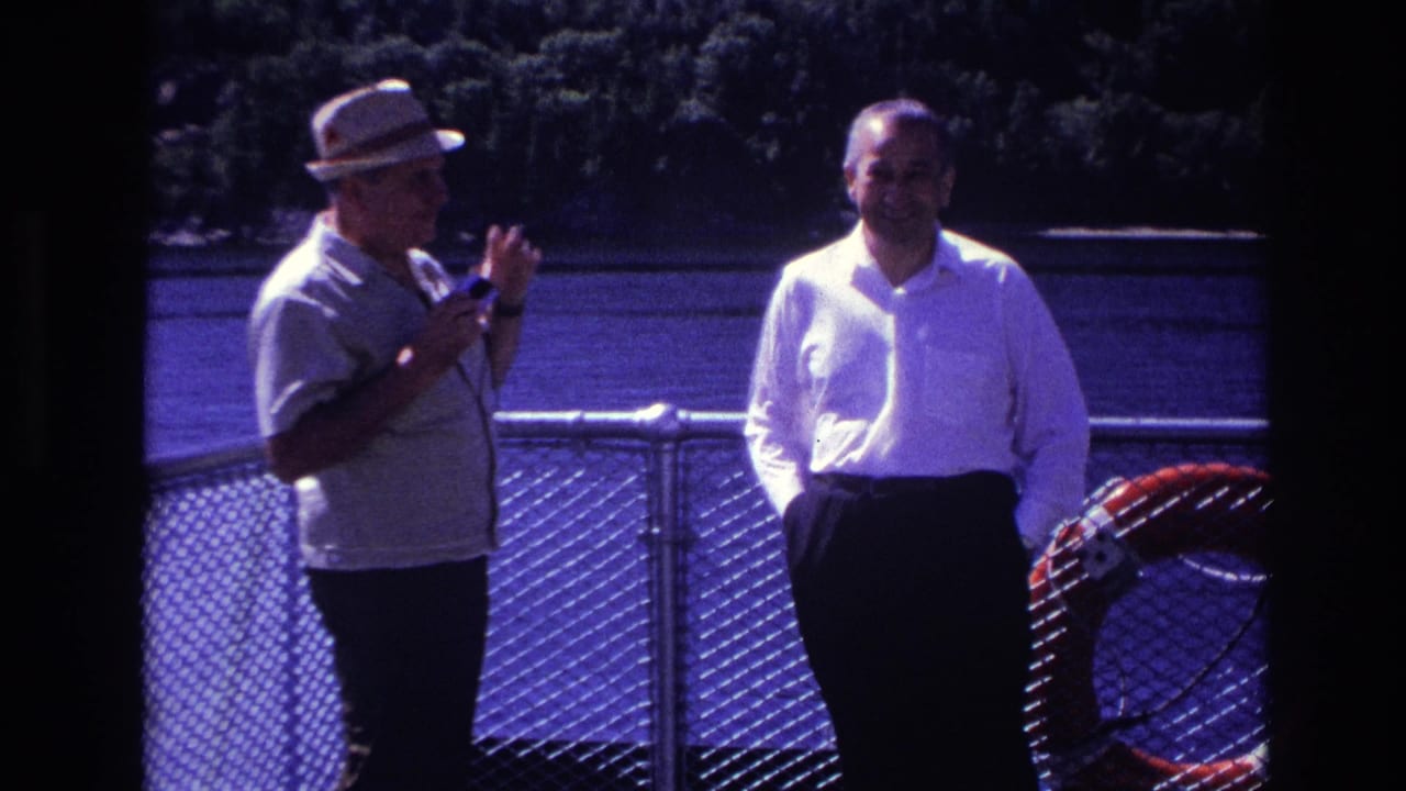 In Ottawa, Canada, 1967 home-movie footage, two men converse near a boat or pier railing with water and trees in the background.