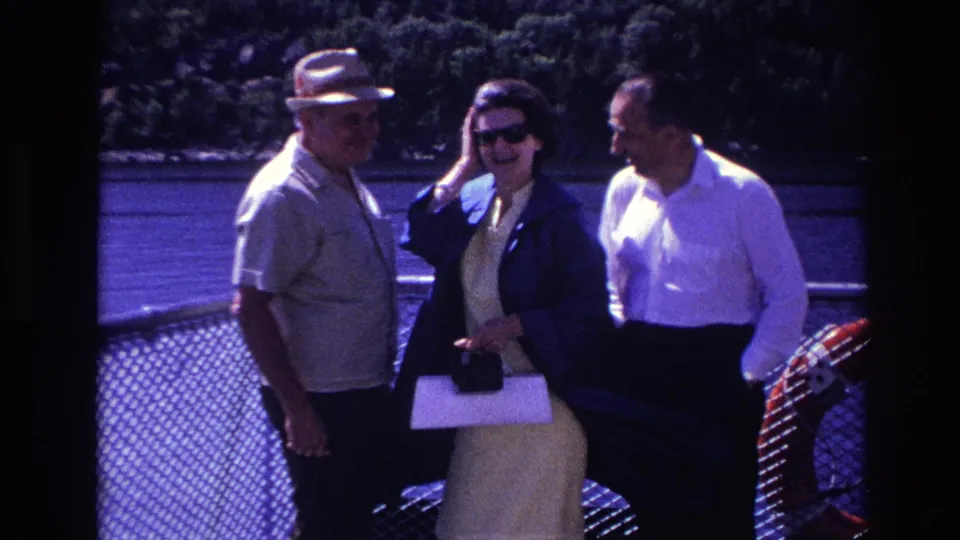 Three adults gather beside a waterfront railing, with the woman holding papers or a purse in 1967 Ottawa home-movie footage.