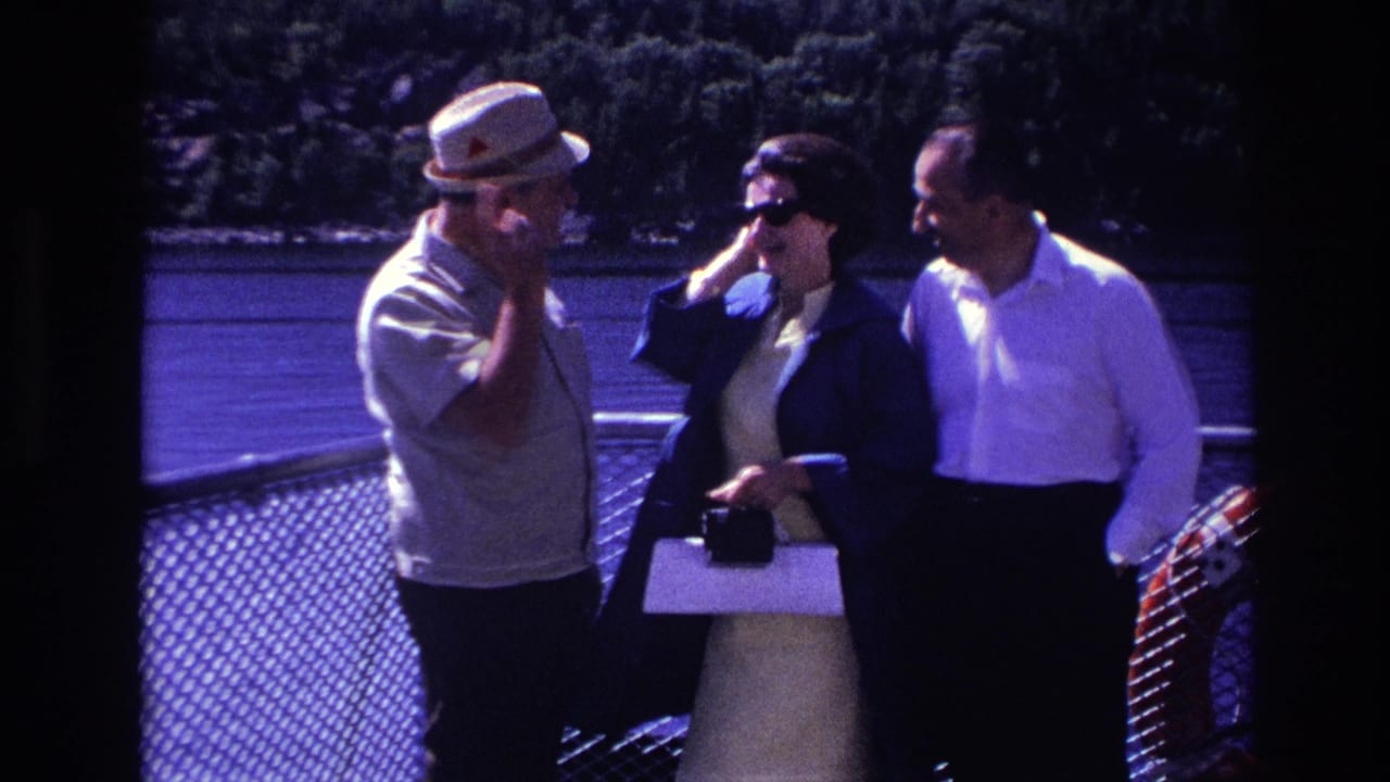 In Ottawa 1967 home-movie footage, three adults stand near a chain-link railing on a boat deck with water and trees behind them.