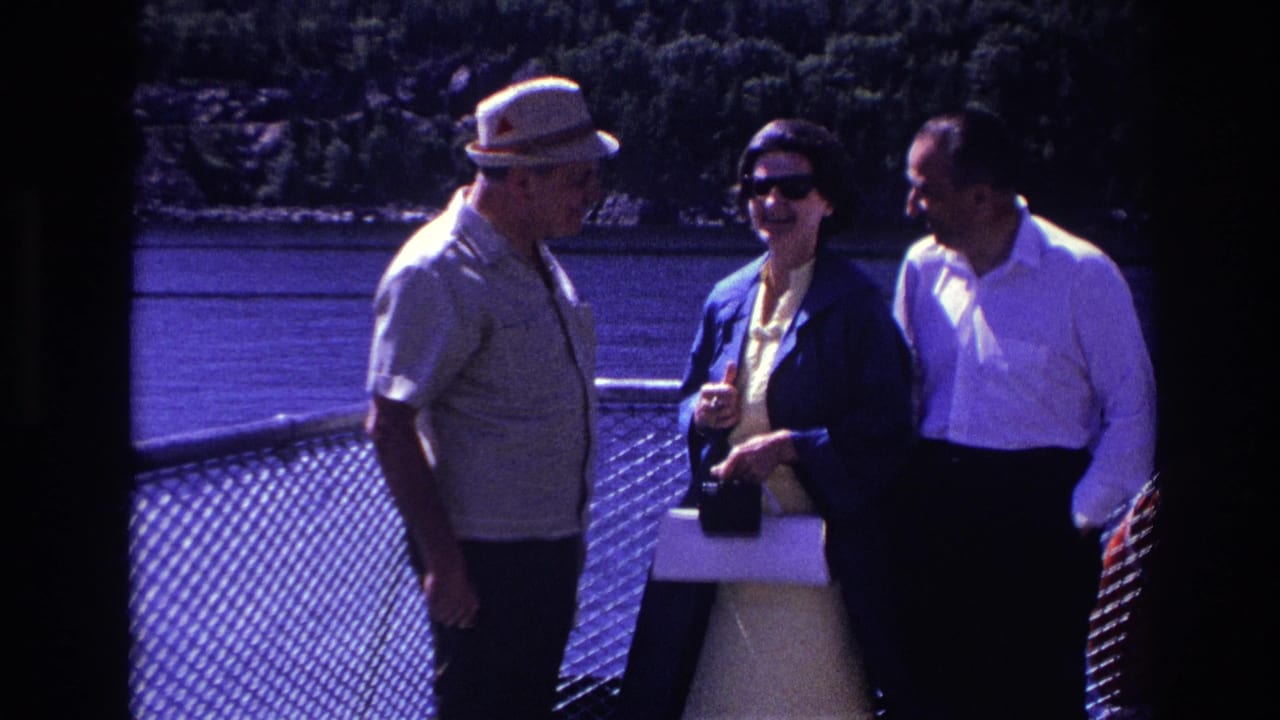 Three adults in 1967 Ottawa footage smile and talk on a boat deck, the woman wearing dark sunglasses and holding a purse.