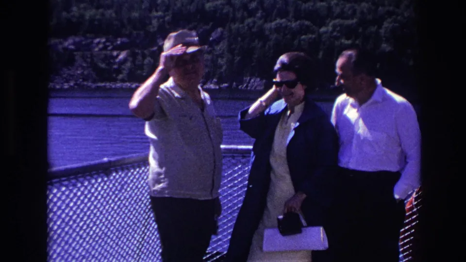 On the Ottawa boat deck, the man touches his hat and the woman adjusts her sunglasses as the group continues their candid exchange.
