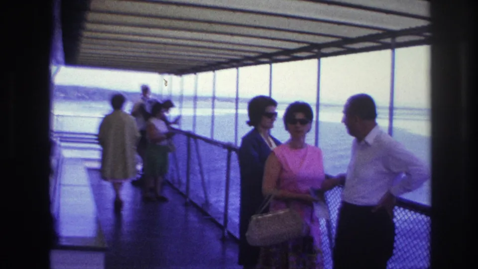 Passengers appear on a covered boat deck in the supplied 1967 Canada travel footage, with two women and a man talking near the railing.