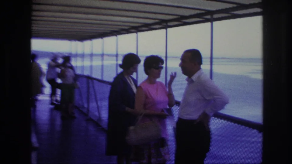 Final frame shows adults in conversation on a covered boat deck, with sunglasses, handbags, railing, calm water, and distant shoreline visible.