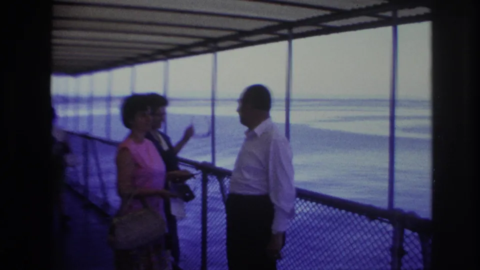 At the end of the 1967 Ottawa boat clip, the woman in pink briefly faces the camera while the man stands in profile near the windows.