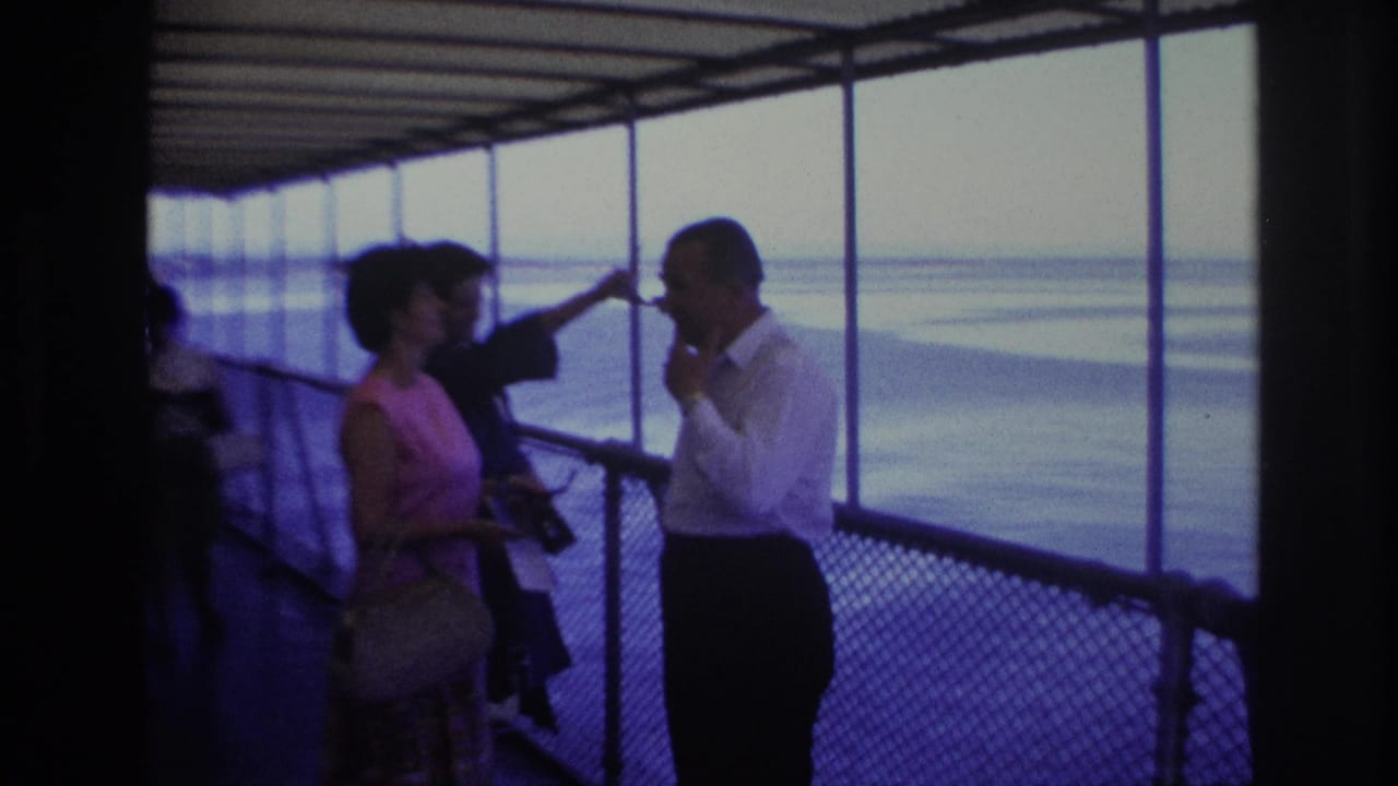 1967 Ottawa metadata frame showing adult tourists under a covered pier structure, with a woman in pink and a man in white near the water view.