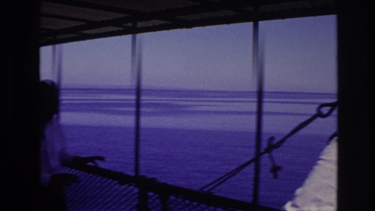 1967 Ottawa home-movie frame showing a silhouetted visitor on a waterfront viewing deck under a covered structure.