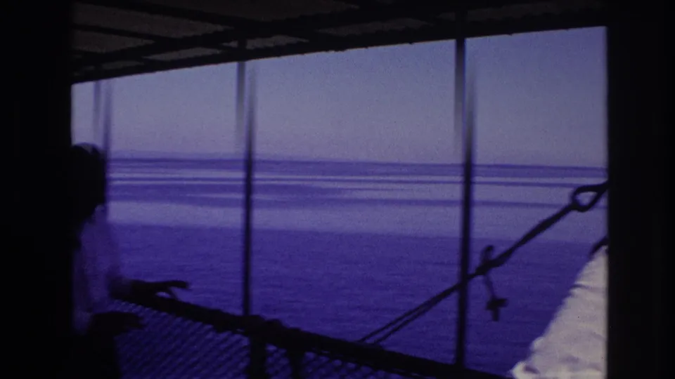 1967 Ottawa home-movie frame showing a silhouetted visitor on a waterfront viewing deck under a covered structure.