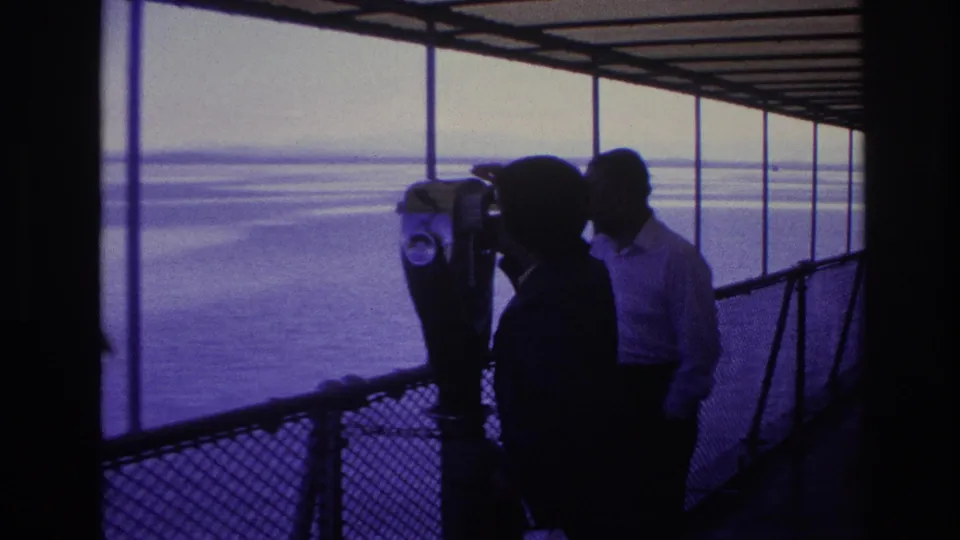 1967 Ottawa frame with silhouetted tourists gathered around a coin-operated binocular viewer overlooking broad water.