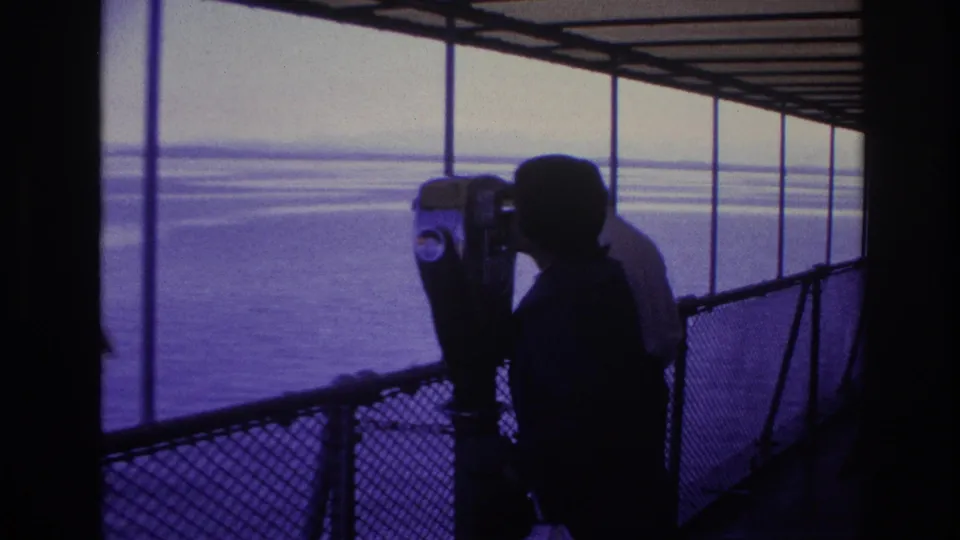 1967 Ottawa frame of a silhouetted visitor using a coin-operated viewer beside railings and open water.