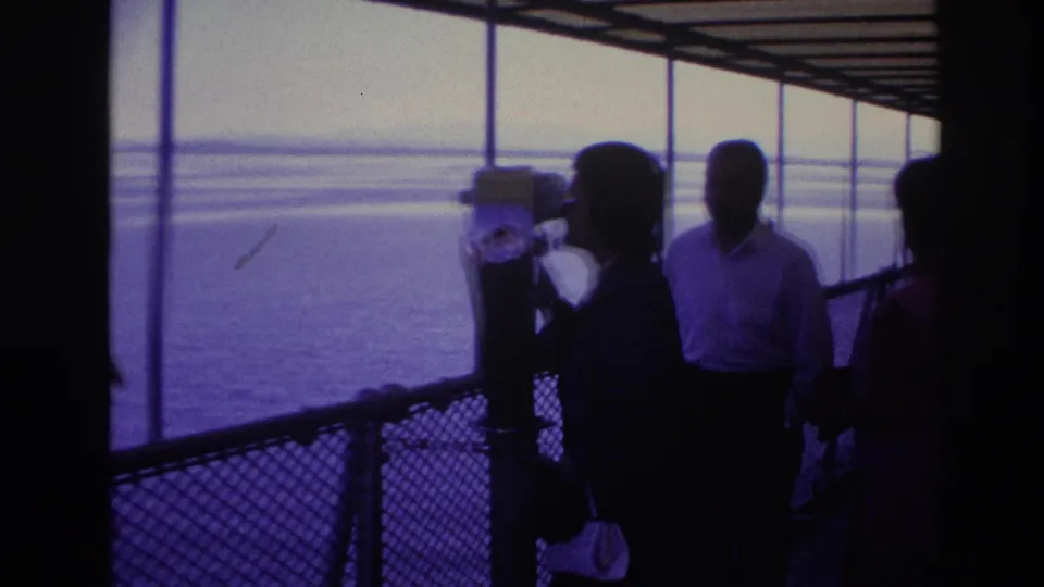 Silhouetted 8mm frame from Ottawa in 1967 with a tourist using a pier-mounted viewer and companions nearby.