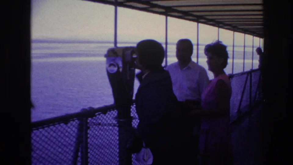 1967 Ottawa home-movie still of adults around a tower viewer on a boat deck, with hazy water and railings in the background.