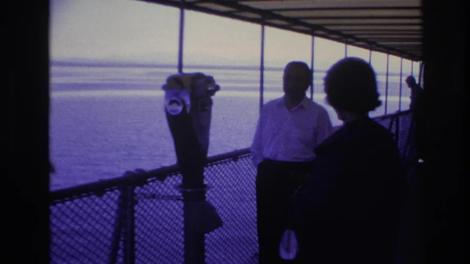 1967 Ottawa deck scene with a man near the railing, a foreground silhouette, and a coin-operated viewer against bright water.