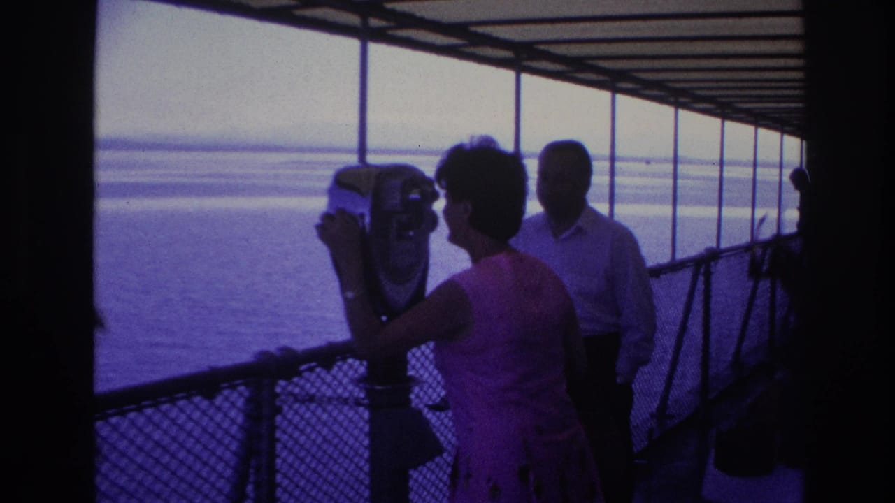 1967 Ottawa home-movie frame with a woman using a deck-mounted binocular viewer as a man stands nearby against the water.