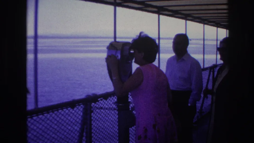 A woman on the 1967 Ottawa boat tour leans toward the coin-operated viewer while adults stand behind her on the shaded deck.