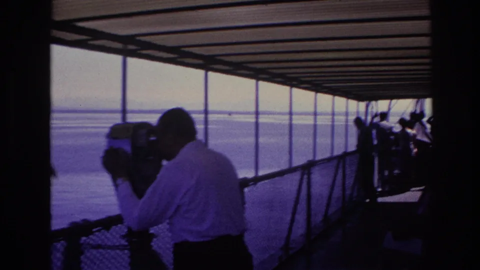 1967 Ottawa boat-deck footage shows a silhouetted man using a coin binocular viewer while passengers stand near the railing.
