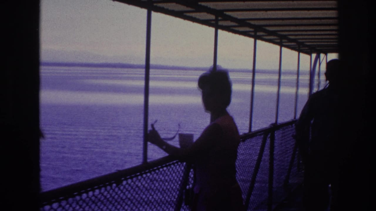 1967 Ottawa home-movie frame showing a silhouetted woman on a covered boat deck looking across calm water.