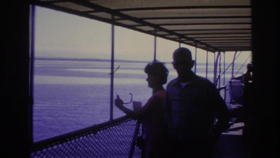 1967 Ottawa home-movie frame with a woman near the railing and a man in a plaid shirt on the boat deck.