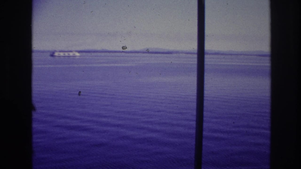 1967 Ottawa, Canada home-movie frame showing purple-tinted water, a distant white passenger ship, and dark window or film-frame bars.