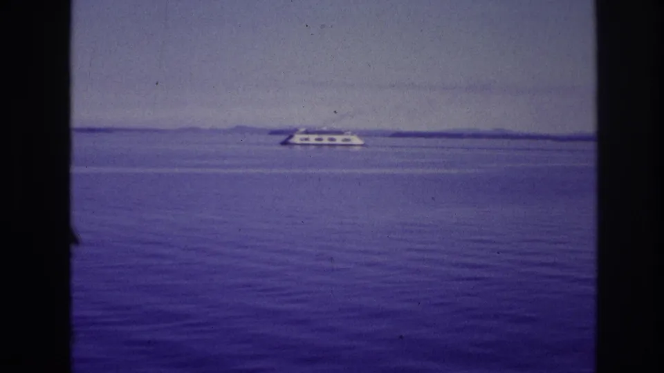 1967 Ottawa, Canada frame with a distant white passenger vessel, flat water, hazy sky, and dark vertical bars from the filming position.