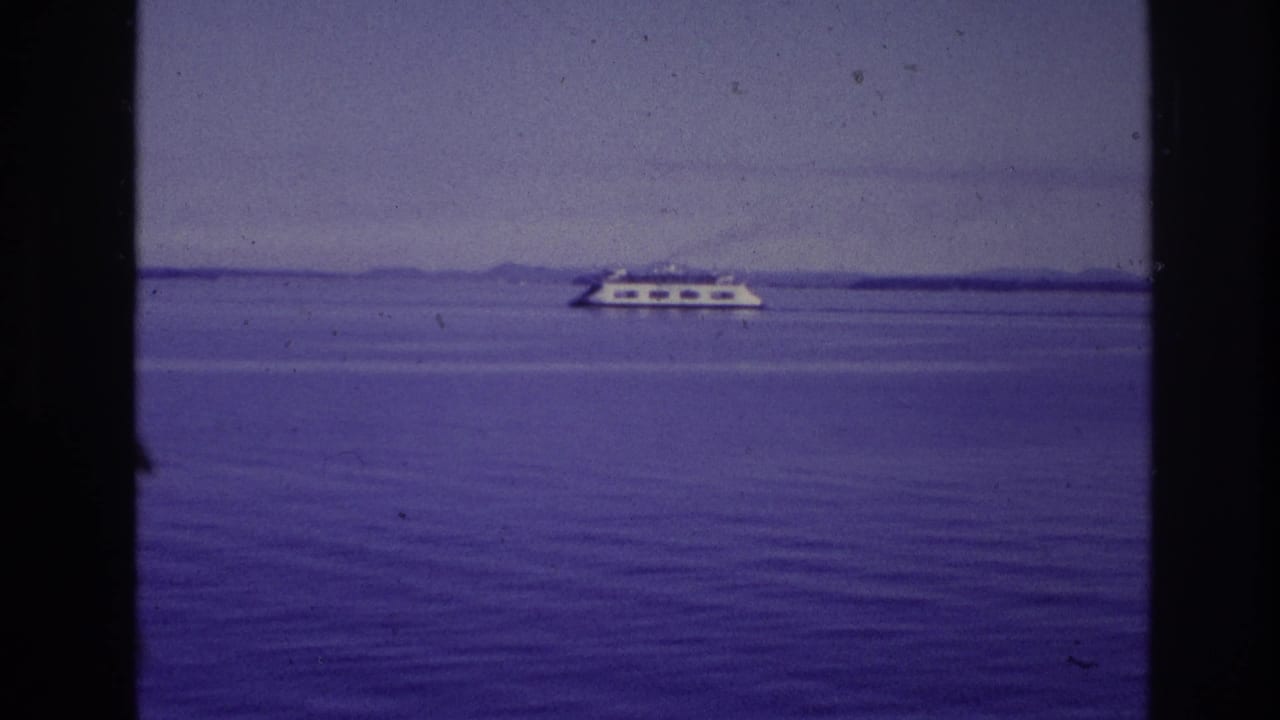 1967 Ottawa-area home-movie frame showing a distant white passenger vessel crossing calm water under a muted sky.