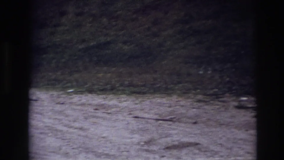 Static 8mm view of a gravel path and grassy slope in Ottawa, with window bars dividing the frame.