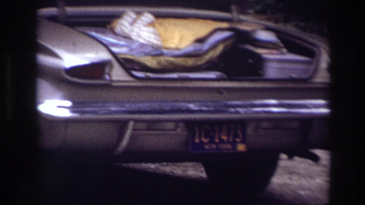Rear of a parked sedan with an open trunk, blankets, and a visible license plate.