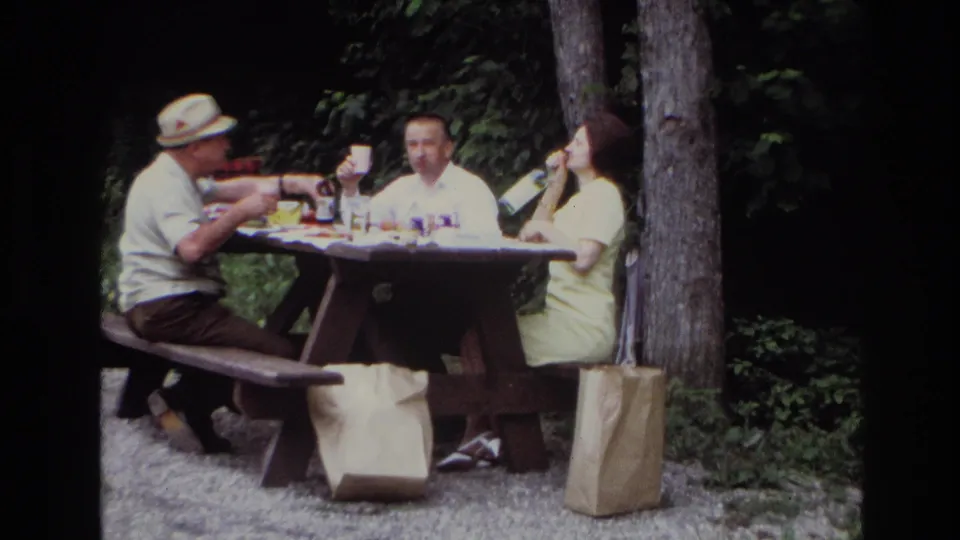 A closer 1967 Ottawa frame shows three adults at a wooden picnic table, with the woman on the right raising a glass or cup.