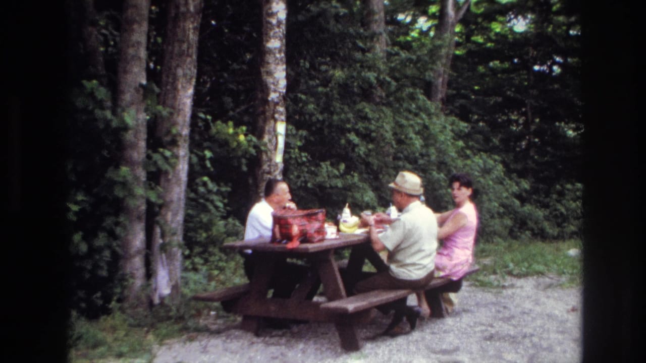 1967 Ottawa frame showing two men and a woman gathered at a wooden picnic table with a red basket and food items.