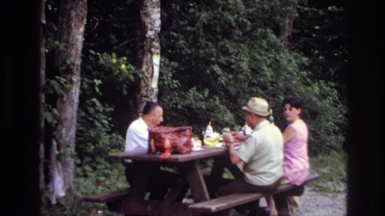 Three adults picnic at a wooden table in a wooded Ottawa-area campsite in 1967 home-movie footage.