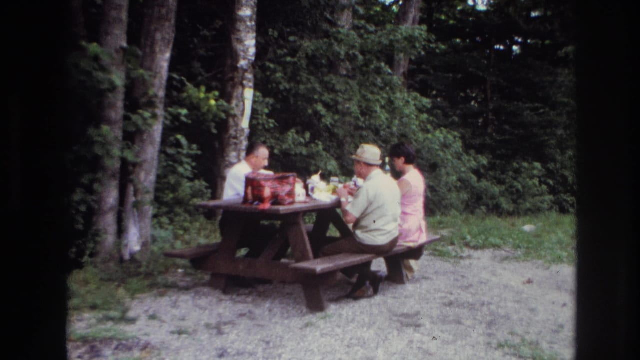 At the end of the 1967 Ottawa clip, the adults remain seated at the picnic table in a wooded setting with soft 8mm color.